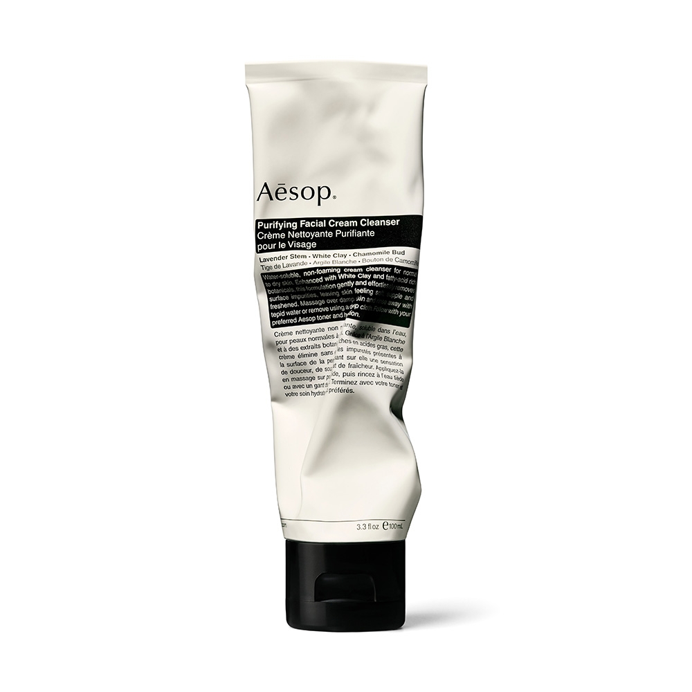 Aesop Purifying Facial Cream Cleanser in a white, slightly crumpled tube with a black cap, featuring product details in black text.