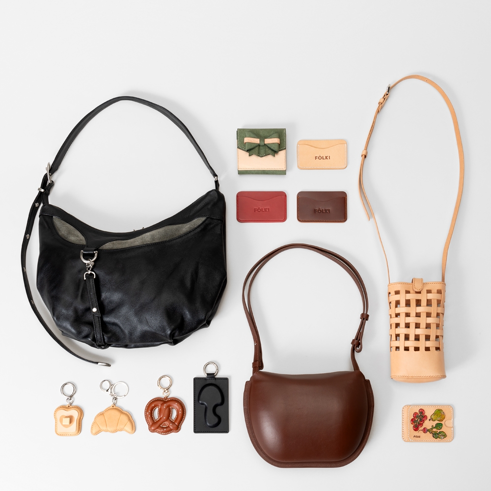 A collection of leather handbags, keychains shaped like bread, and small leather card case arranged neatly on a white background.