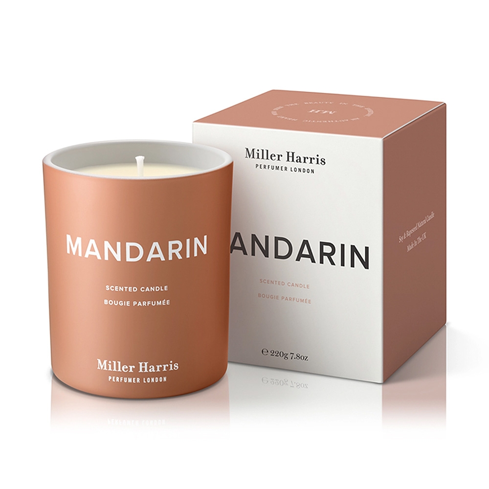 オレンジ色の容器に入ったMiller Harrisのマンダリンの香り付きキャンドルと、その隣にあるマッチする箱。両方に白い文字でラベルが貼られている。