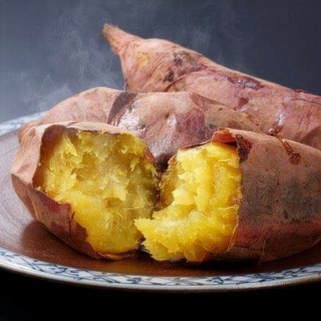 Steaming roasted sweet potatoes on a plate, with one split open to reveal its golden, tender interior.