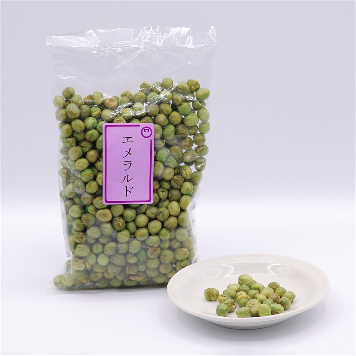 A bag of green wasabi peas with Japanese text on the label, next to a small white plate containing some of the peas.