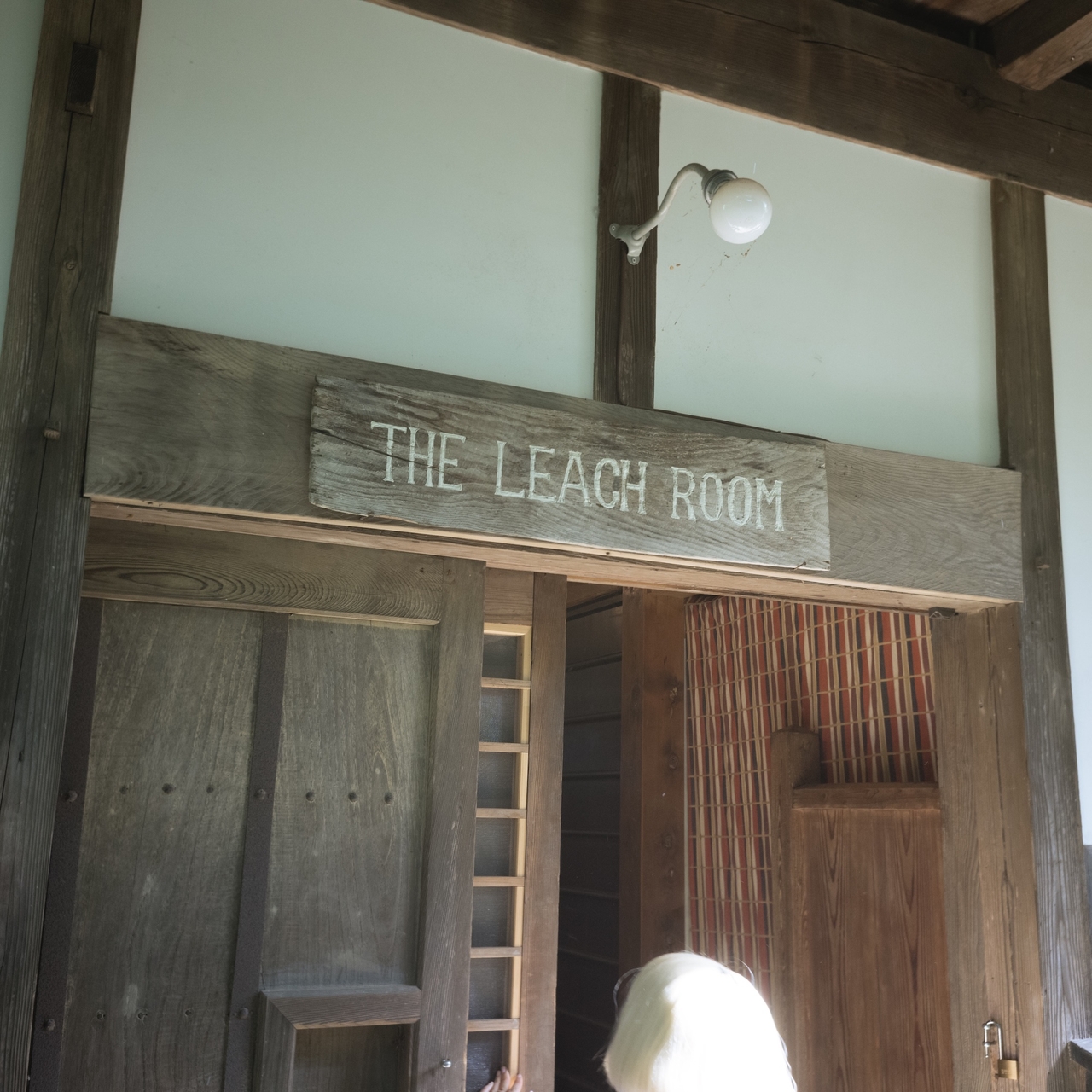 Wooden doorway labeled "The Leach Room" with a rustic light fixture above, leading into an interior space with wooden accents.