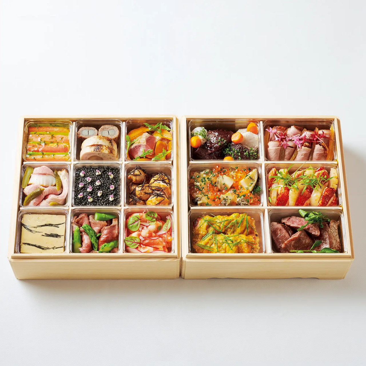 Two wooden boxes each with a grid of twelve compartments, filled with assorted colorful and artfully arranged food items.