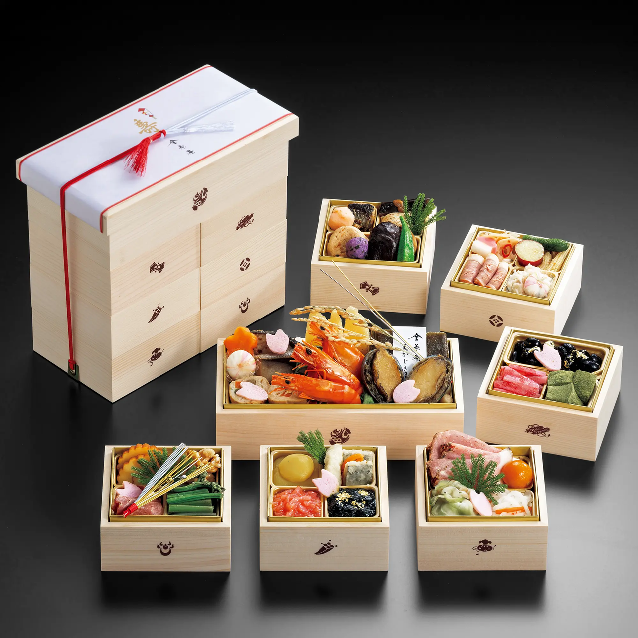 Elegant wooden boxes filled with assorted traditional Japanese foods, including seafood and vegetables, arranged aesthetically for a special occasion.