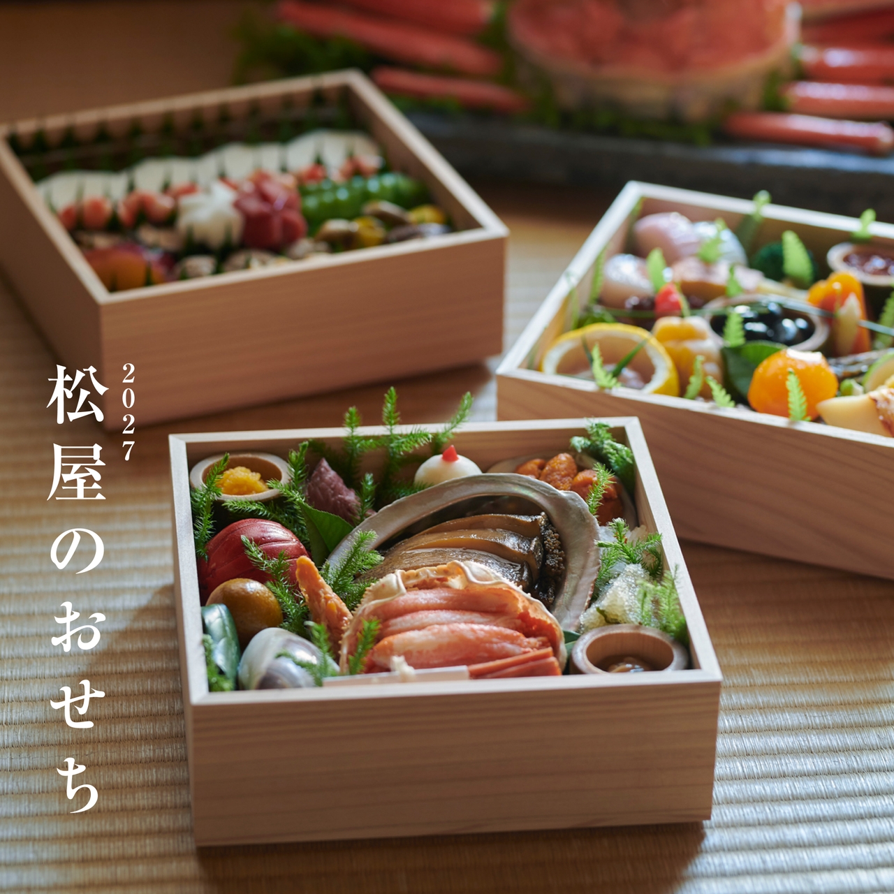 木製のテーブルの上に、色とりどりの魚介類や野菜が盛り付けられた、伝統的な日本のおせちの重箱が並んでいる。側面には「2027松屋のおせち」のロゴ。