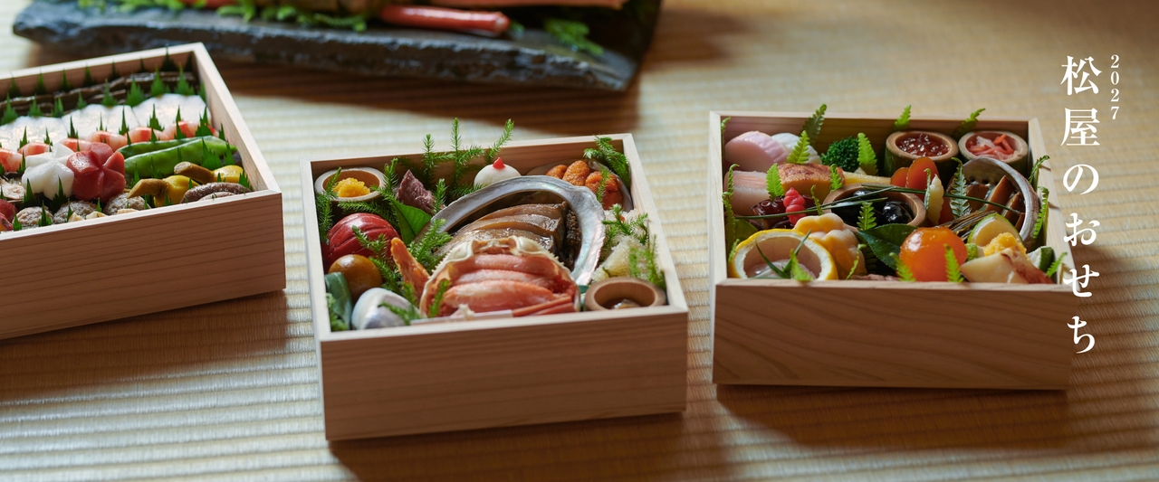 木製のテーブルの上に、色とりどりの魚介類や野菜が盛り付けられた、伝統的な日本のおせちの重箱が並んでいる。側面には「2027松屋のおせち」のロゴ。