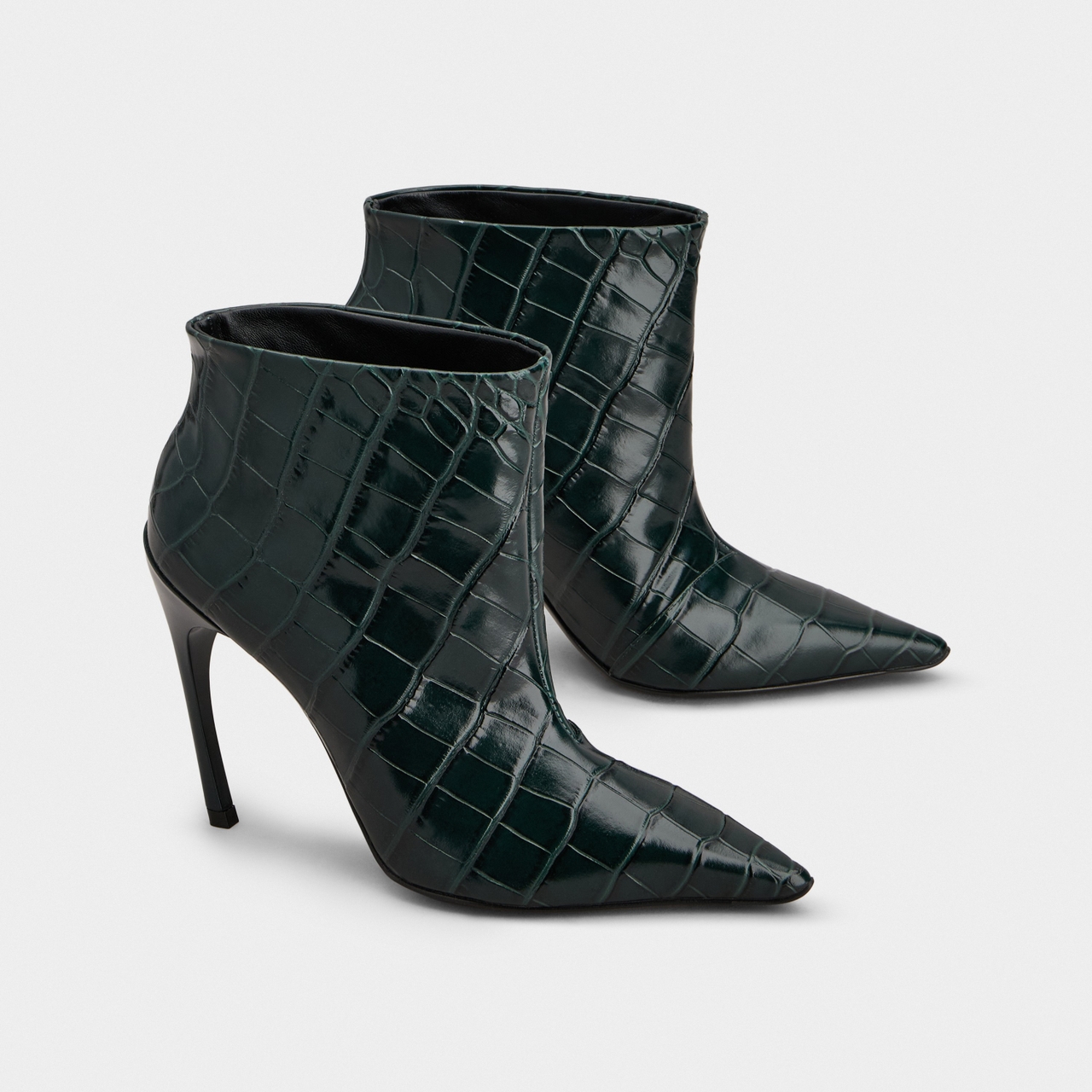 Dark green, crocodile-patterned, pointy-toed ankle boots with stiletto heels on a white background.