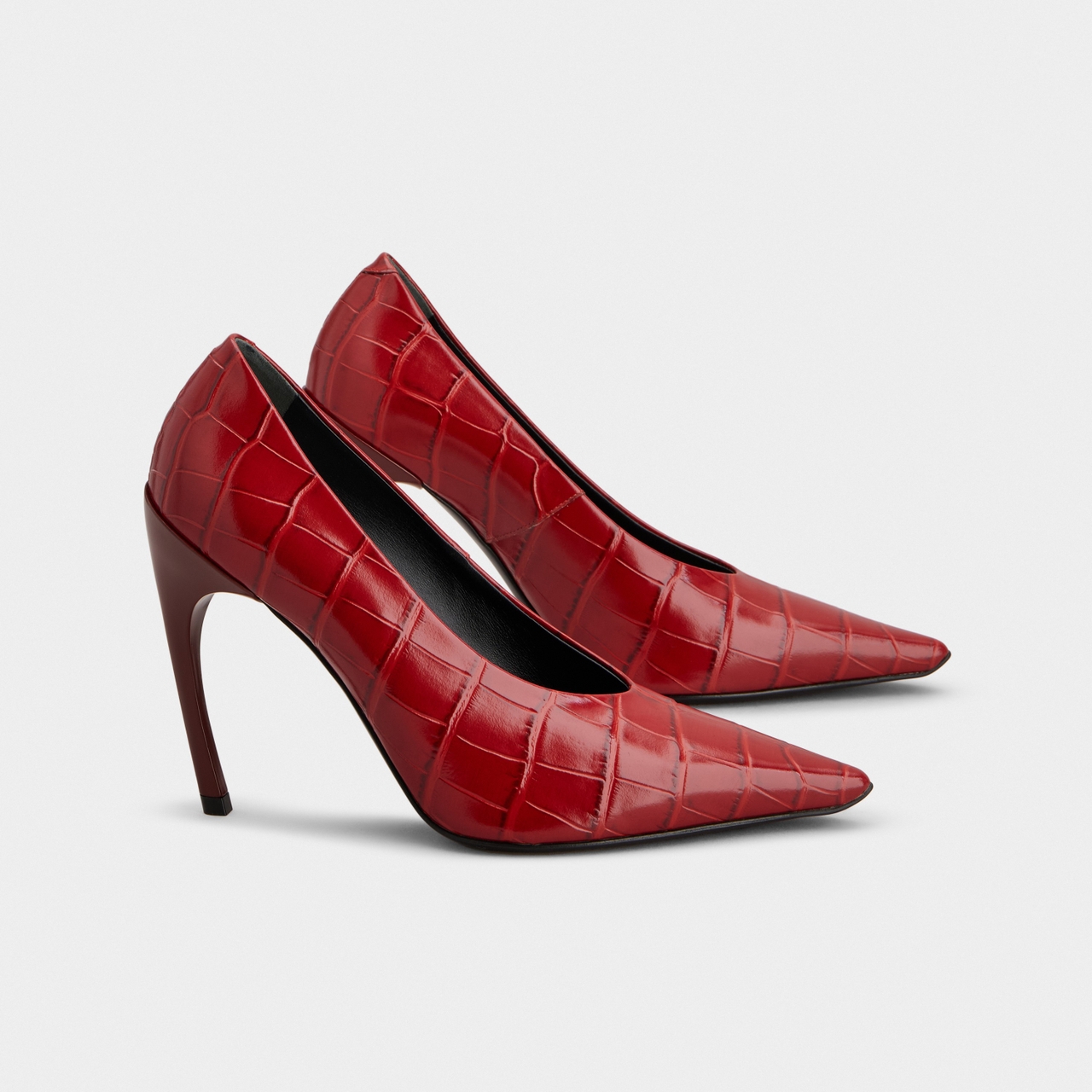 Red crocodile-patterned high-heeled pumps with pointed toes against a plain background.