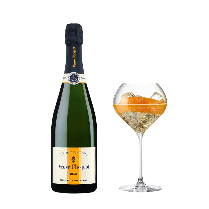 A bottle of Veuve Clicquot Rich on Ice champagne next to a glass filled with ice and an orange twist.